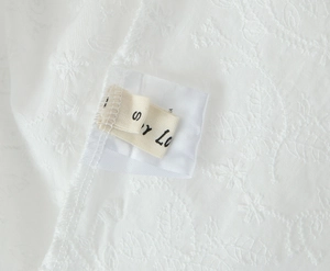 Gros plan sur l'étiquette taille S d'une robe en dentelle blanche à texture tissée