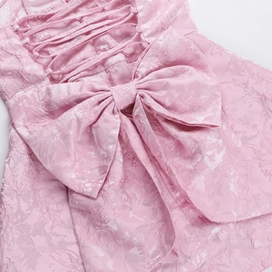 Détail du dos d'une mini robe en jacquard rose avec laçage corset et un grand nœud