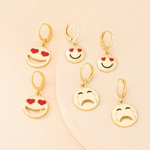 Detailed view of gold emoji earrings featuring heart-eye and teary face expressions