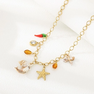 Détail d'un collier en acier doré avec pendentifs piment rouge, étoile de mer et dauphin