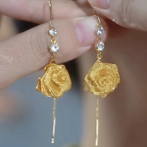 Detailed macro view of matte gold rose earrings with zircon accents and long chain tassels