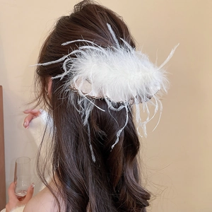 Detail of white fluffy feather hair clip accessory worn on brunette wavy hair