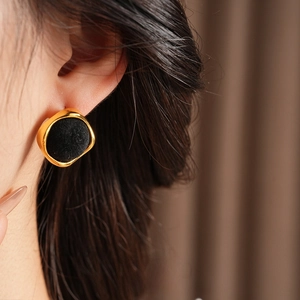 Boucles d'oreilles géométriques noires floquées avec bord doré portées par un mannequin