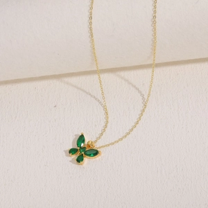 Macro shot of gold-plated necklace featuring a green butterfly pendant with crystal wings