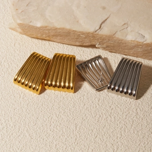 Dettaglio di orecchini a trapezio in oro e argento con trama a strisce verticali su pietra