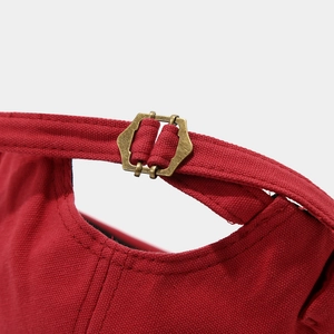 Detailed macro view of the dark red canvas cap with an adjustable bronze hexagonal buckle