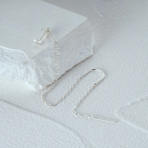 Macro shot of silver star stud earrings with long tassel chains on a stone texture