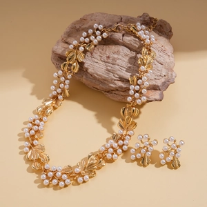Vintage gold leaf and pearl necklace set with matching earrings on a natural stone base