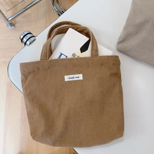Brown corduroy tote bag with white label on a minimalist table, top view aesthetic