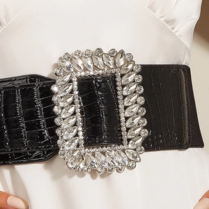 Close-up of black crocodile-embossed wide belt featuring a large crystal rectangular buckle