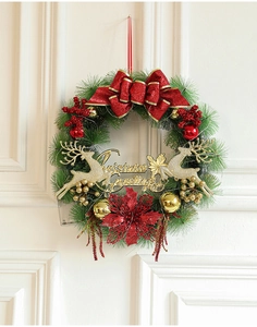 Close-up of lighted Christmas wreath with red bow, gold reindeer and festive ornaments