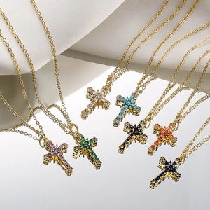 Gold-plated cross pendant necklace set with multicolor zircon gemstones on a mirror