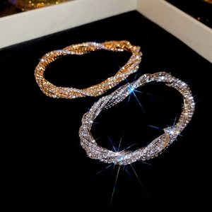 Detail of silver and gold multilayered rhinestone twist bracelets on black velvet