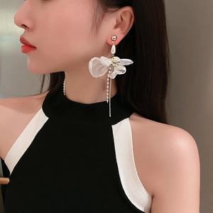 Detail view of elegant lace bow earrings with pearls and long chain tassels on a model