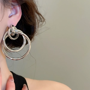Gros plan de boucles d'oreilles argentées multicouches polies sur un modèle féminin