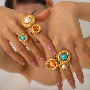 Close-up of bohemian gold rings set with turquoise and pearl on a person's fingers
