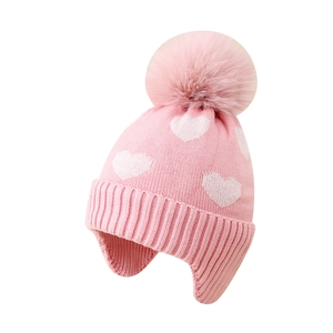 Pink winter knit trapper hat for girls with white heart patterns and a fluffy pompom