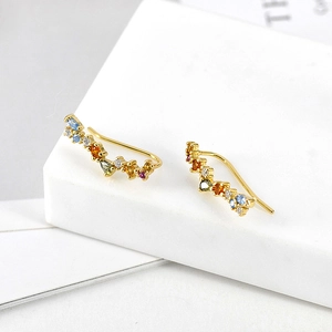 Macro shot of colorful zircon ear climbers with gold plating on a stone surface
