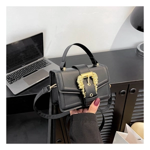 Detail of elegant black crossbody bag featuring ornate gold baroque buckle and top handle