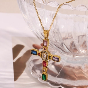 Détail du pendentif croix plaqué or 18K serti de pierres colorées sur bord en verre