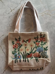 Close-up of intricate double-sided floral embroidery on a beige canvas tote bag