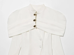 Detail of white blazer jacket with exaggerated shoulders and decorative gold buttons