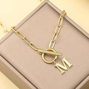 Gold letter M pendant necklace with OT toggle clasp on a velvet jewelry display box