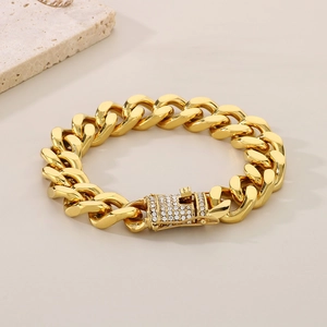 Close-up of golden Cuban link bracelet featuring a CZ-encrusted clasp on stone prop