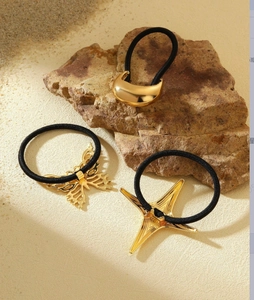 Detailed shot of gold butterfly and star metal hair ties on natural stone and sand