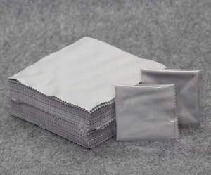 Close-up of light gray microfiber cleaning cloths with zigzag edges in bulk and individual bags