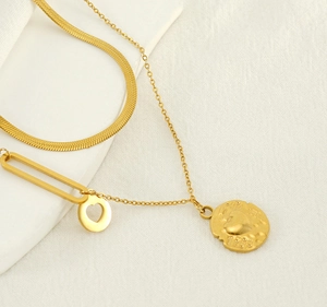Detail of double-layer golden necklace with snake chain and hollow heart pendant