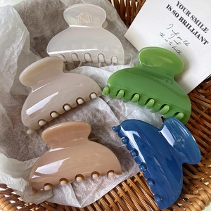 Set di cinque mollette per capelli lucide in colori assortiti in un cesto intrecciato
