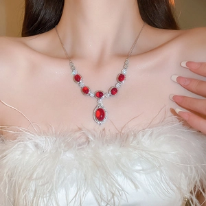 Detailed view of silver flower necklace with red gemstone and cubic zirconia on model