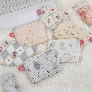 Flat lay of multiple quilted cotton makeup bags with cartoon patterns and zippers