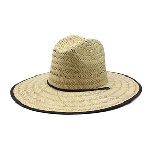 Detail of natural straw sun hat featuring black fabric binding and adjustable wind cord