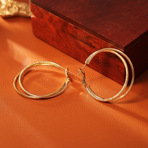 Detail of gold double-hoop earrings featuring one smooth and one textured glitter ring