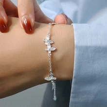 Detail of silver bracelet with three butterfly charms and sparkling zircon stones on wrist