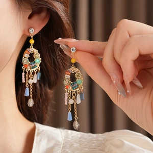 Détail de boucles d'oreilles bohèmes à pompons colorés avec perles et cristaux sur mannequin