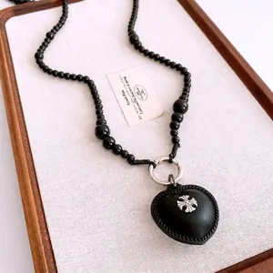 Gothic beaded necklace with a black leather heart pendant and silver cross emblem detail