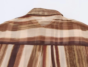 Dettaglio posteriore di una camicia in chiffon a righe marroni e beige semitrasparente