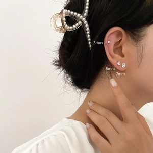 Detail shot of 3mm, 6mm, and 7mm silver zirconia stud earrings worn in layers