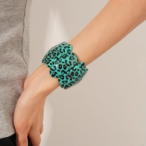 Gros plan d'un large bracelet élastique à motif léopard turquoise sur le poignet