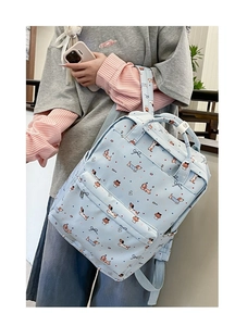 Detail shot of light blue backpack with cartoon dog prints worn by a model in soft light