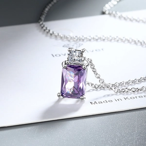 Macro shot of silver necklace with rectangular purple gemstone and white zircon pendant
