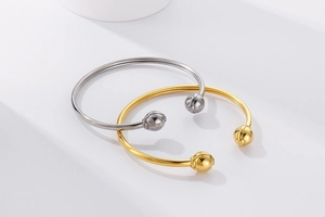 Close-up of minimalist gold and silver stainless steel open bangles with sphere ends