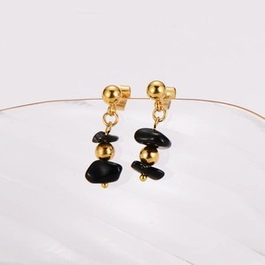Elegant gold earrings with black natural stone beads displayed on a transparent tray