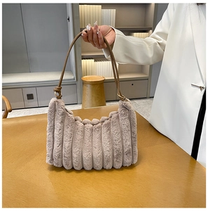 Borsa beige in peluche con texture a coste e tracolla in pelle marrone su modella