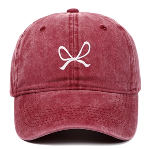 Close-up of embroidered white bow on washed cotton burgundy vintage baseball cap