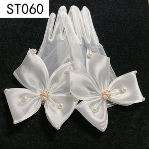 Detail of white bridal mesh gloves with large satin bow, pearls, and rhinestones