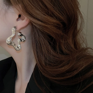 Close-up of polished silver irregular wave earrings worn by a model in dark suit